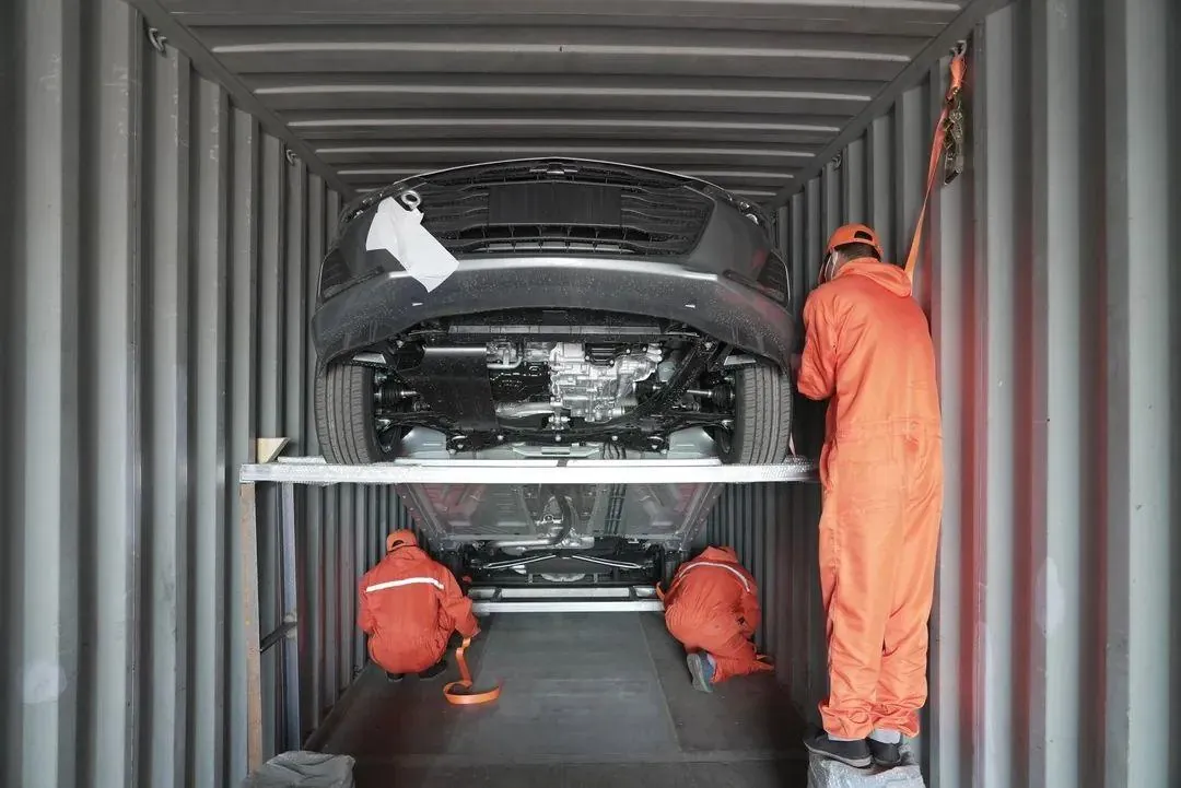 Crew securing a car inside a shipping container